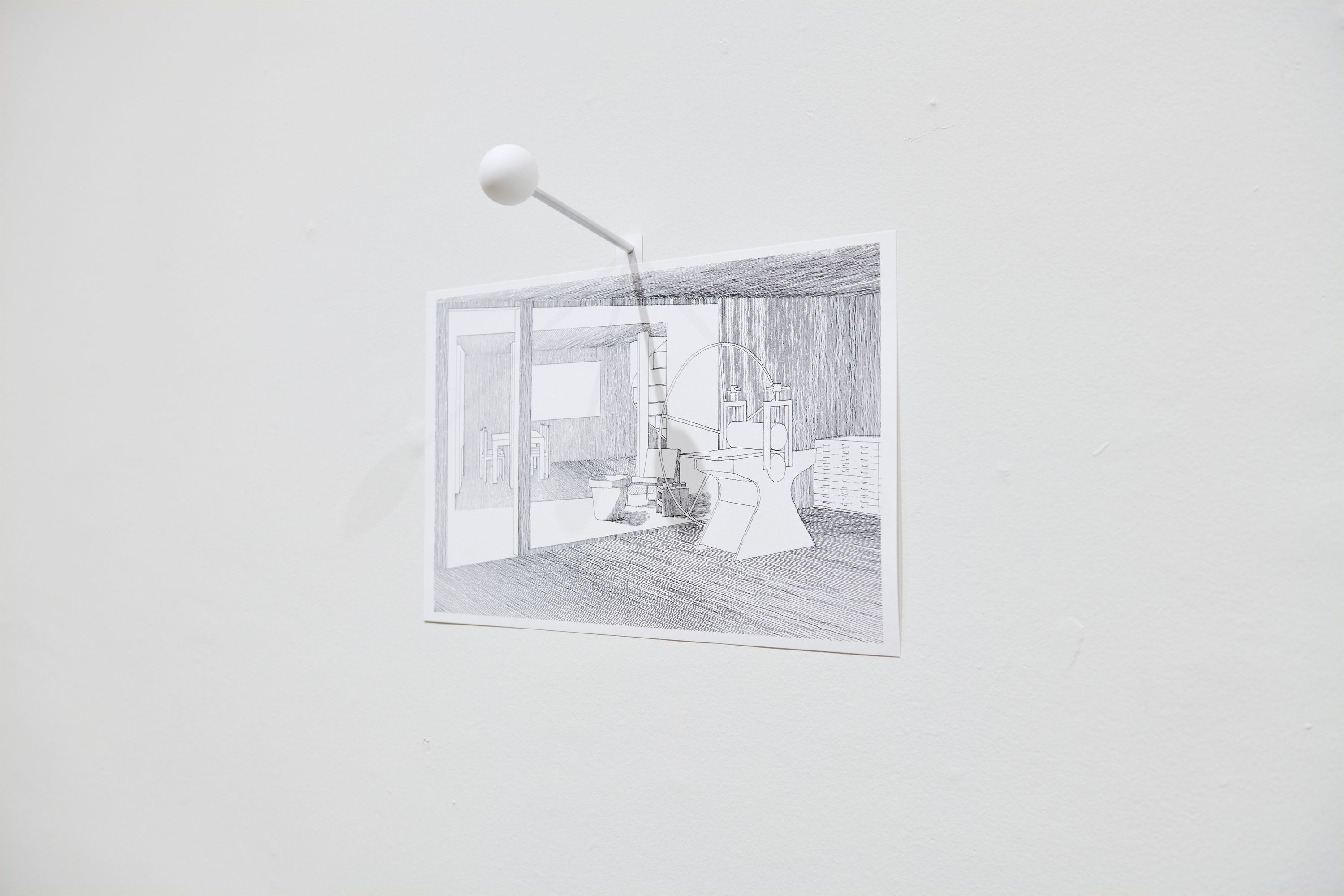 Photograph of print hung on gallery wall with a large pin appearing 5x the normal size